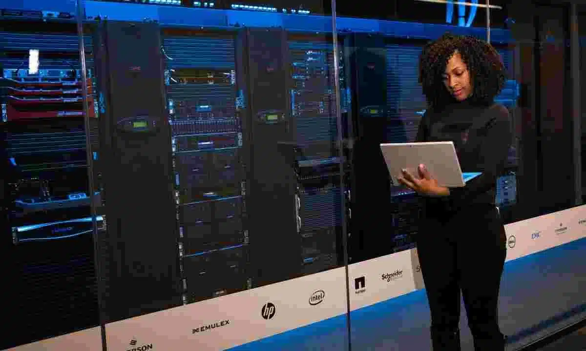 مهندسة تقنية أمام سيرفرات مركز بيانات، تحمل جهاز لوحي وتشرح مواصفات السيرفرات